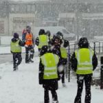 People wearing high-visibility vests participating in winter safety training outdoors.