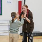 Engaging child and adult high-five at ACE Voices event promoting communication and inclusion.
