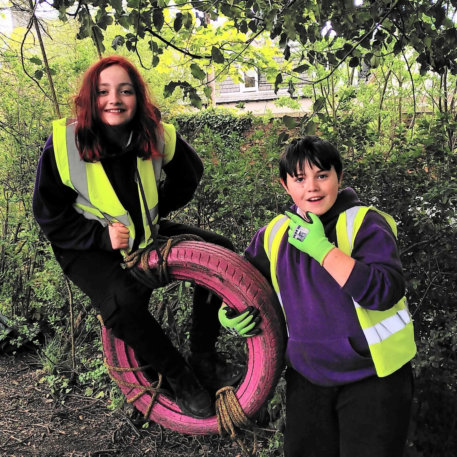 Young volunteers in high-visibility vests participating in community clean-up activity.